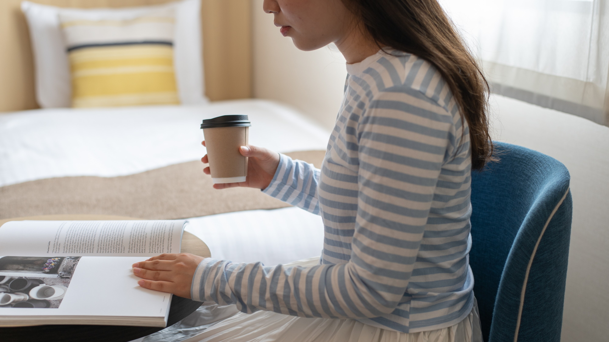 In-room lifestyle at Hotel Vista Fukuoka — guest relaxing with book and coffee in a standard room