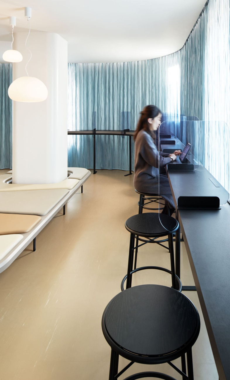 9h nine hours smart check-in area — tablet terminals and counter seating behind blue curtain divider