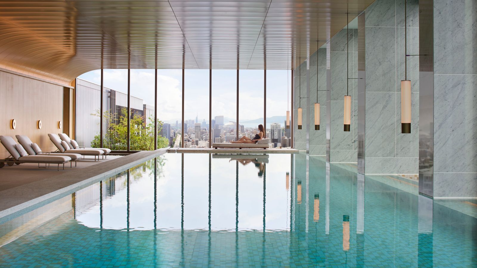 The Ritz-Carlton Fukuoka indoor infinity pool with panoramic Fukuoka city skyline view through floor-to-ceiling windows